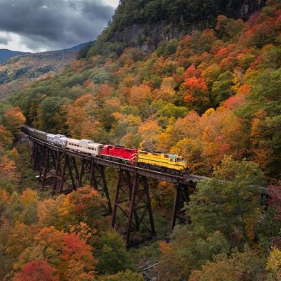 New Hampshire fall foliage with train crossing bridge