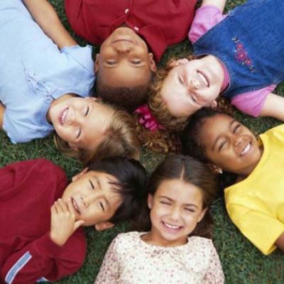 diverse children laying on the grass in a circle looking up at the sky
