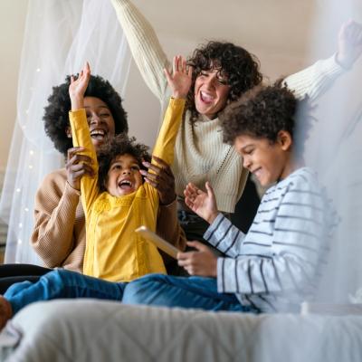 Image of family with hands up and sitting on a bed