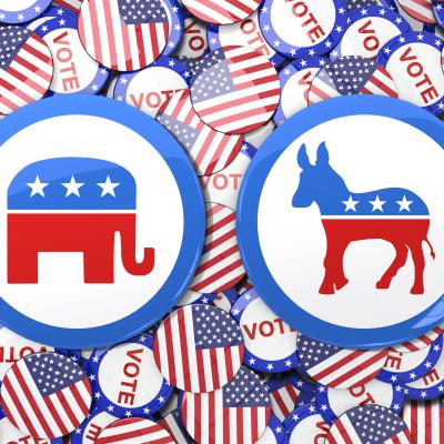 two large election buttons, one with an elephant and the other with a donkey, over a background of smaller buttons with the American flag and the word 'vote' on them