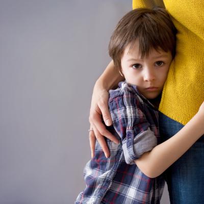 young boy looks worried as he's comforted by his mother