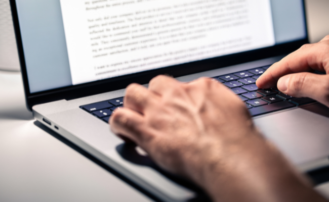 Stock photo of a person typing a letter on a laptop